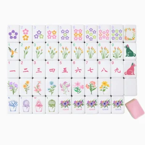 Neat flat lay display of luxury Floral Breeze Mahjong Tiles with illustrated floral, animal, wan, wind and joker face tiles, a cutaway tile reveals white, purple, green and pink 4-layer build.