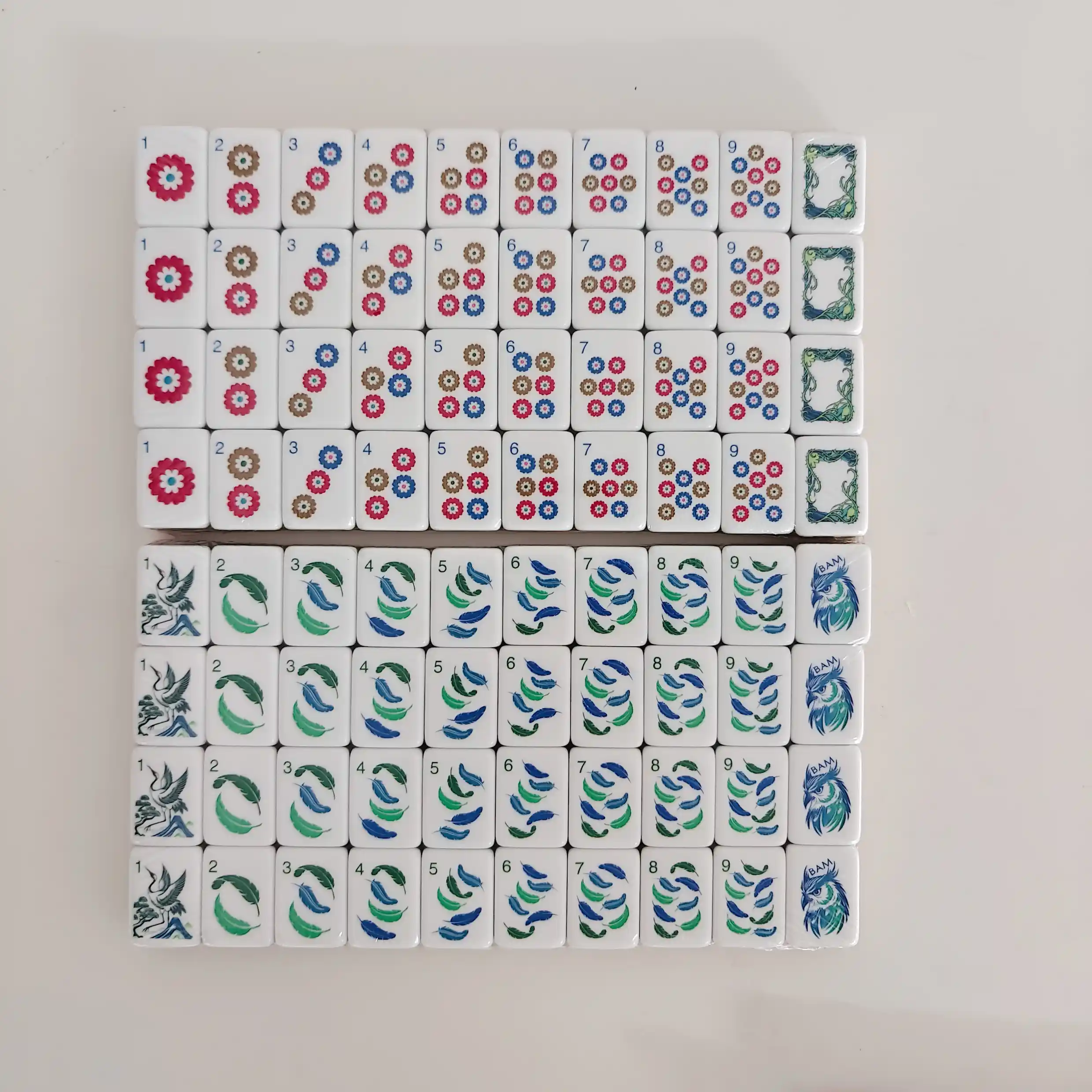 OMHJGO Cranes & Feathers mahjong Dot tiles 1-9 featuring chrysanthemum medallions in crimson blue and brown, plus Bam tiles 1-9 with flowing feather brushwork and crane 1-Bam illustration