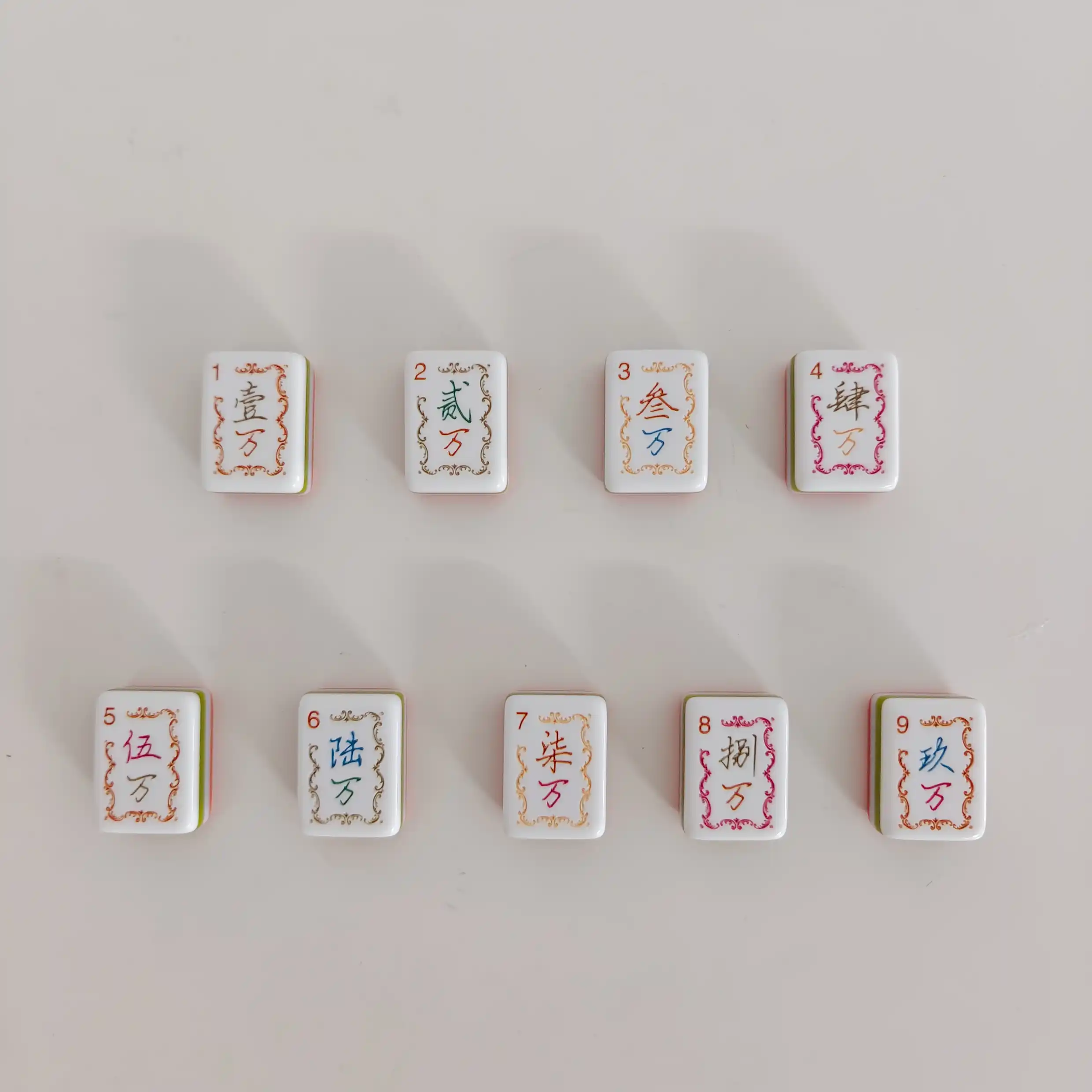 OMHJGO mahjong Crakes & Feathers series Crak tiles 1 through 9 featuring ornate calligraphy numerals in multicolor rococo borders on white acrylic