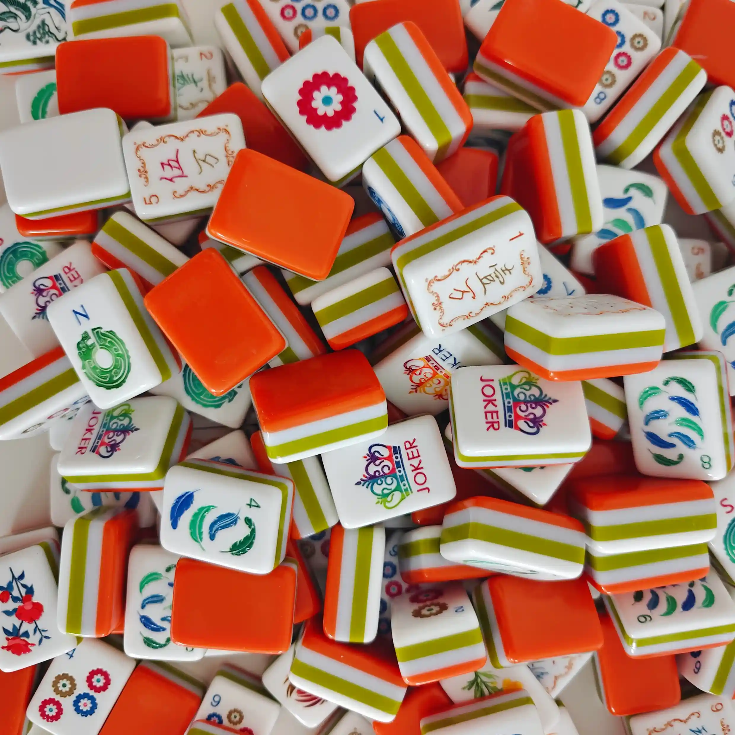 Close-up macro shot of OMHJGO Cranes & Feathers acrylic mahjong tile backs featuring bold orange high-gloss polished acrylic surface