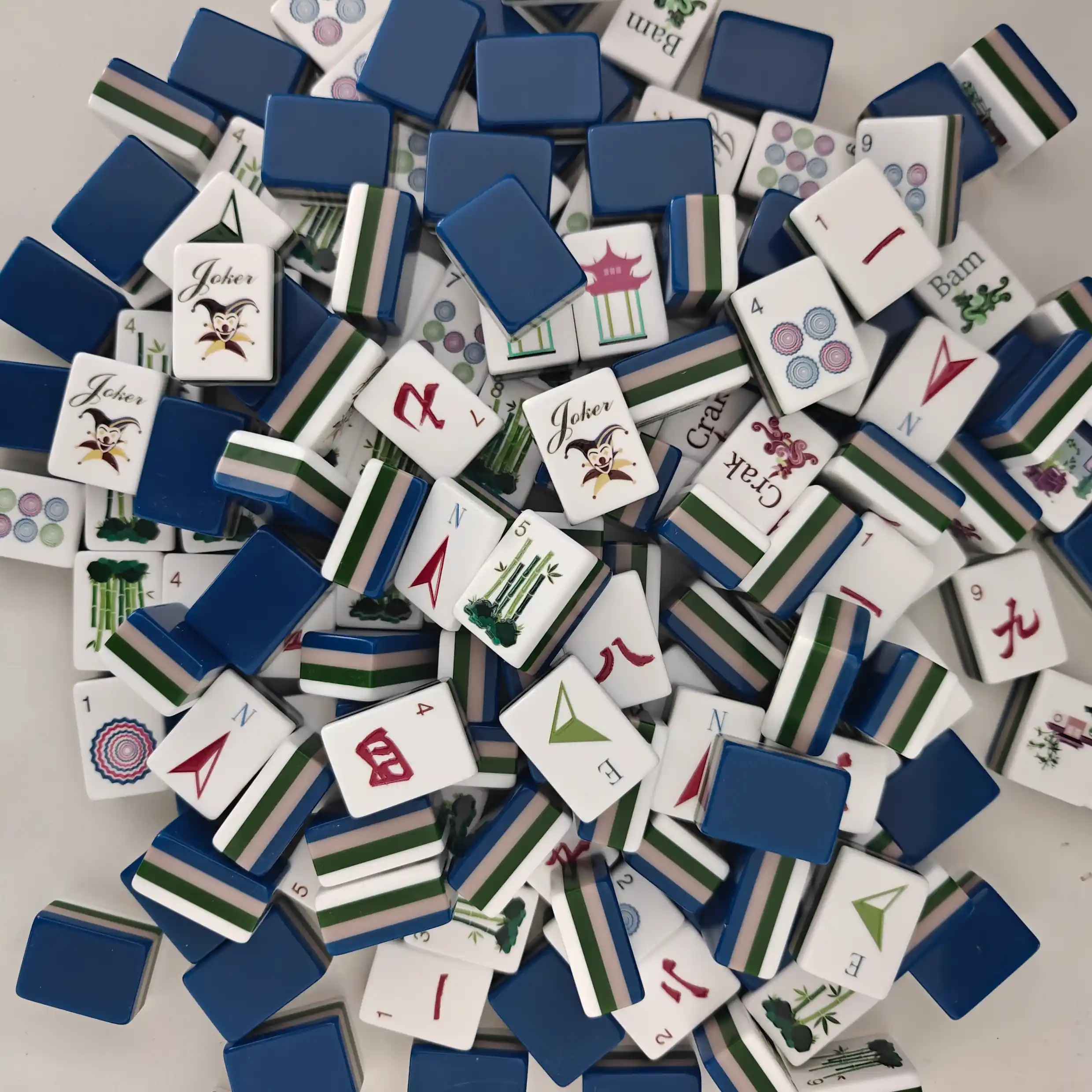 Scattered messy pile of luxury 4-layer acrylic mahjong tiles featuring the high-gloss navy blue backing profile.