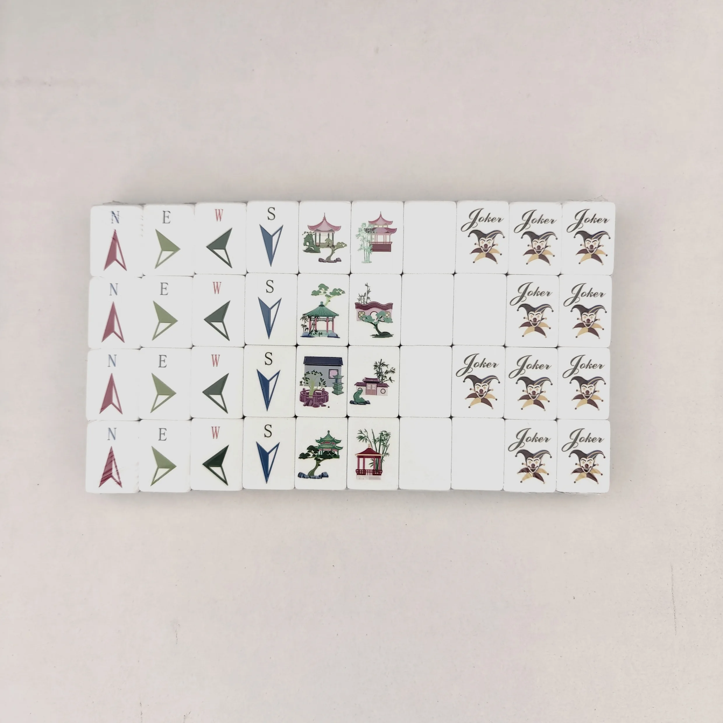 Compass wind symbols, traditional courtyard garden pavilions, and festive court jester jokers on acrylic mahjong tiles.