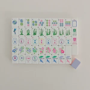 Balanced layout of mixed suits and flower tiles with a turned-over lavender purple backing tile.