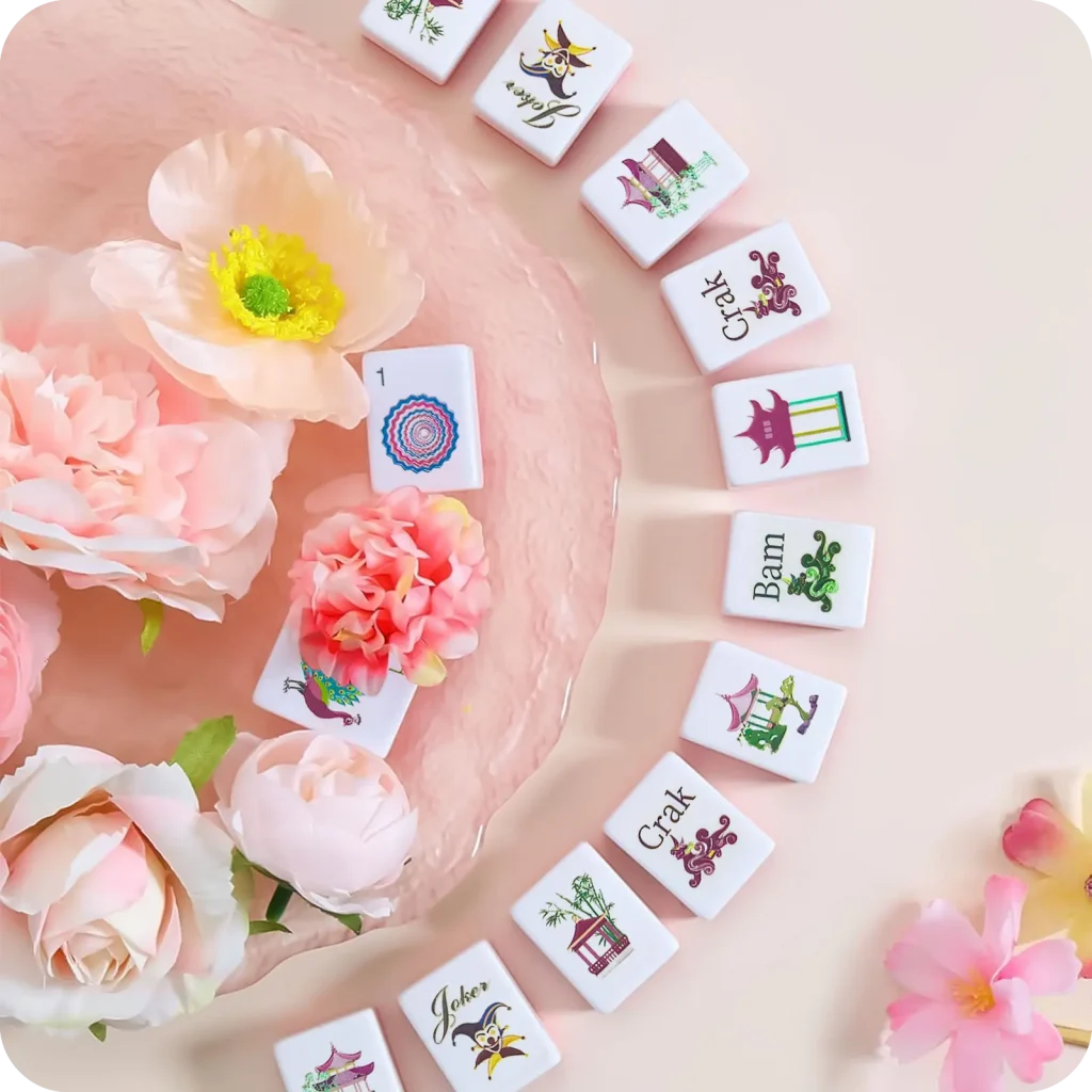Flat lay aesthetic shot of Pagoda Breeze Mahjong Tiles scattered with soft pink peony flowers, used for Mahjong Gift Guide